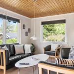 Living room with leather sofa, wooden ceiling, and view of green trees.