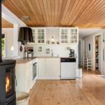 Kitchen with wooden floor, white cabinets, and wood-burning stove. View of garden through window.