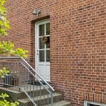 Red brick building with white door and steps to entrance.