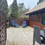 Terrasse mit Liegestühlen und Sitzgruppe vor einem Holzhaus mit Schieferdach.