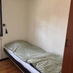 Schlafzimmer mit Einzelbett, Fenster und Kleiderschrank.
