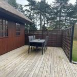 Terrasse mit Tisch und Stühlen neben einem Holzhaus mit Dach aus Stroh.