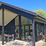 Modern wooden cabin with large covered outdoor area and grill.