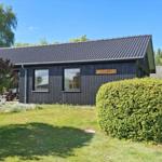 A house with dark cladding and green garden. A sign with the name Hygghly.