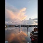 Sunset over harbor with boats and reflection in the water