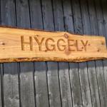 Wooden sign with the inscription HYGGELY on a dark wooden wall.