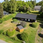 Black house with terrace and garden. Surrounded by trees and green areas.