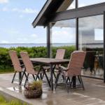 Terrace with table and chairs. View of water and greenery. Glass front to interior.