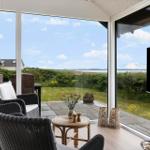 Glass veranda with seating and view of green fields and water.