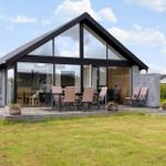 Modern villa with large glass area and outdoor terrace with seating.