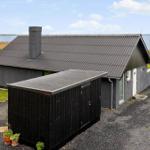 Modern gray cabin with chimney and garage by water.