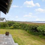 Terrace with view of green area and water. Wind turbine and house in background.