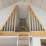 Wooden railing and ladder lead to a vaulted ceiling with stone walls.