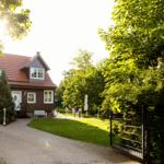 Ein Haus mit rotem Dach, weißer Tür und Gartenbereich mit Liege.