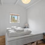 Bedroom with white bed, window and wooden floor.