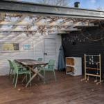 Deck with table, chairs, and toys under pergola with string lights.