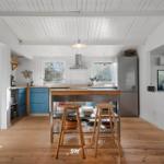 Kitchen with wooden floor, blue cabinets, and kitchen island with stools.