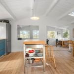 Kitchen with dining area and workspace. Wooden floor, white walls and ceiling beams.