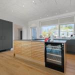 Moderne Küche mit Holzinsel, integriertem Kühlschrank und großen Fenstern.
