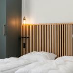 Schlafzimmer mit Holz-Kopfteil, weißer Bettwäsche und schwarzem Schrank.