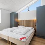 Schlafzimmer mit Doppelbett, Holzfußboden und großen Fenstern.