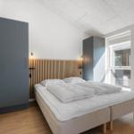 Schlafzimmer mit Bett, Holzdecke und Fenster. Zwei Schränke an den Wänden.