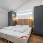 Schlafzimmer mit Doppelbett, Holzoberseite, zwei Schränken und Fenster.