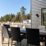 Terrasse mit Tisch und Stühlen neben einem Haus mit Glasfront.