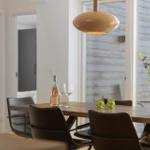 Esszimmer mit Holztisch, Stühlen und Blumenarrangement. Hängelampe und Fenster sichtbar.