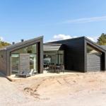 Moderne Holzhütte mit großem Terrassenbereich und Sitzgelegenheiten im Freien.
