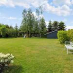 Large garden with lawn, play equipment, benches, and plants.