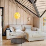 Wohnzimmer mit Sofa, Tisch und Holzwand. Decke mit Balken und Lampe.