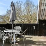 Terrasse mit Tisch, Stühlen, geschlossenem Sonnenschirm und Grill.