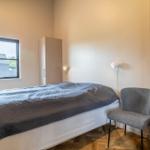 Schlafzimmer mit Bett, Stuhl und Kleiderschrank. Fenster mit Blick auf Dach.