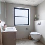 Badezimmer mit Waschbecken, Toilette und Fenster. Handtuch hängt an Wand.