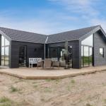 Moderne Strandhaus mit Terrasse, Gartenmöbel und Schiebetüren zur Außenterrasse.