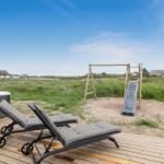 Terrasse mit Liegestühlen, Whirlpool und Kinderspielplatz im Freien.