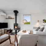 Living room with fireplace, sofa, and TV. Wooden floor and white walls.