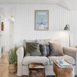 A living room with a sofa, cushions, and a picture on the wall.