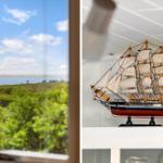 Through the window, a landscape with water and greenery is visible. In the room, a wooden ship model stands.