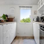 Kitchen with white cabinets, wooden countertops, and window view of trees.
