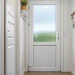 Entrance with white door and frosted glass. A key holder and a plant are on the wall.