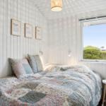 Bedroom with bed, window, and wall shelves. Ceiling and walls are white clad.