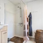 Bathroom with shower, sink and toilet. Wooden vanity, wicker basket and shower curtain.