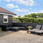 Terrace with seating group and sun loungers. Backyard with hedge and blue sky.