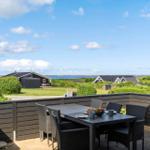 Terrace with table and chairs, view of green areas and water.
