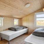 Two beds in a wooden house with windows and wooden ceiling.