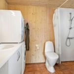 Bathroom with shower, toilet, and washing machine. Wooden wall and terracotta floor.