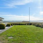 House with garden, view of water and bridge under blue sky.
