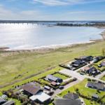 Aerial view of houses by a lake with a bridge in the background.